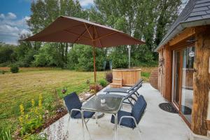 a table with chairs and an umbrella on a patio at Le chouette insolite in Cresseveuille