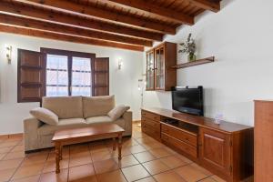 a living room with a couch and a tv at Apartamentos El Rincón de Bustio in Bustio
