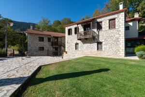 a large brick house with a large grass yard at Guest House Amadryades in Karpenisi