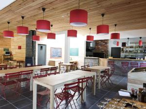 um restaurante com mesas e cadeiras e luzes pendentes vermelhas em Huttopia Royat em Royat