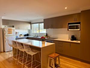 a kitchen with a counter and a island with bar stools at Eunoia at Smiths in Smiths Beach
