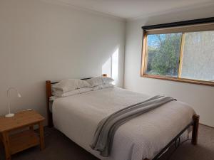a white bedroom with a bed and a window at Eunoia at Smiths in Smiths Beach