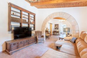 a living room with a large television and an archway at Casa Vista Monte in Llucmajor