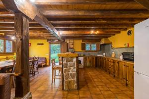 a large kitchen with yellow walls and wooden ceilings at La Hirriria in San Roque de Ríomiera