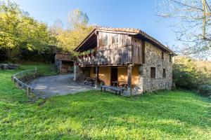 an old stone building with a bench in a field at La Hirriria in San Roque de Ríomiera