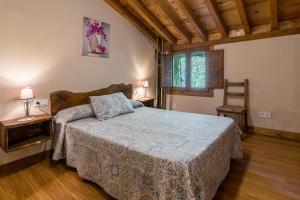 a bedroom with a bed and two tables and a window at La Hirriria in San Roque de Ríomiera