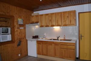 a kitchen with wooden cabinets and a sink and a microwave at Appartement La Petite Cascade in Allos
