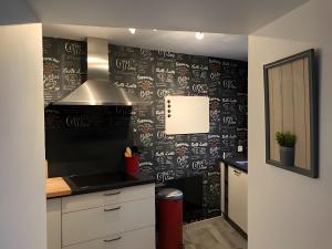 a kitchen with a black wall with writing on it at Gîte Les Aubennes in Fromelennes