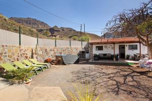 a patio with chairs and a house with mountains in the background at Vv Tasartico in San Nicolás