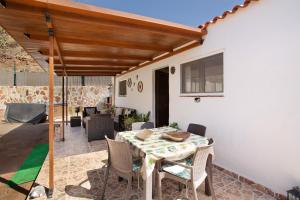 a patio with a table and chairs and a wooden pergola at Vv Tasartico in San Nicolás