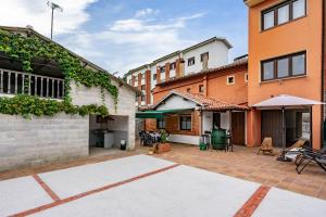 an outdoor patio with tables and chairs and buildings at Ca Carmina in Colunga