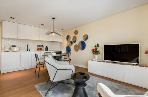 a kitchen and living room with white cabinets and a flat screen tv at Casa D'avó Amália in Travanca