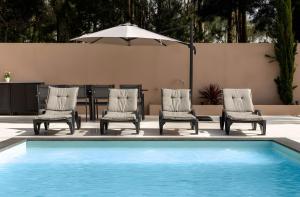 three chairs and a table with an umbrella next to a pool at Casa D'avó Amália in Travanca