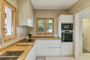 a kitchen with white cabinets and a sink at Villa la Barrufa in S'agaro