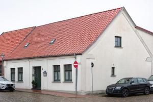 a white building with an orange roof with two cars parked in front at Studio zur »Alten Schmiede« in Laage