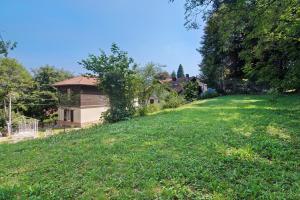 a grassy hill with a house in the background at Residenza ai Noci in Lanzo dʼIntelvi