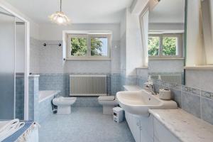 a bathroom with a sink and a toilet and a tub and sinks at Residenza ai Noci in Lanzo dʼIntelvi +21 photos