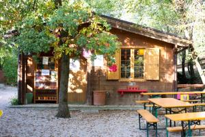 a small wooden cabin with tables and a tree at Colleincanto Appartamento Torretta in Gavardo