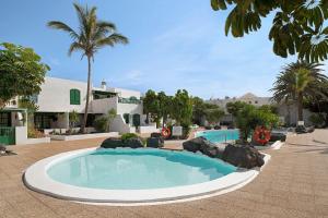 a swimming pool in a resort with palm trees at Apartamento Rocas Negras in Puerto del Carmen
