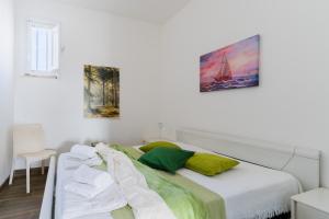 a white bedroom with a bed with green pillows at Casa Azzurra a Torre dell'Orso in Torre dell'Orso