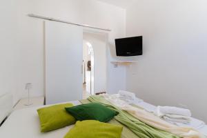 a bedroom with a bed with green pillows and a television at Casa Azzurra a Torre dell'Orso in Torre dell'Orso