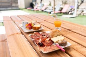 a wooden table with two plates of food and a glass of orange juice at A Casa Assulanata Cinto in Santa-Reparata-di-Balagna