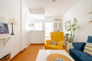a living room with a blue couch and a yellow chair at 1 Linea Playa , 3 Dorm Islantilla in Isla Cristina