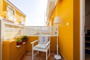 a room with a white chair and a yellow wall at 1 Linea Playa , 3 Dorm Islantilla in Isla Cristina