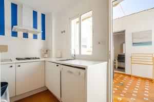 a kitchen with white cabinets and blue accents at 1 Linea Playa , 3 Dorm Islantilla in Isla Cristina