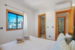 a white bedroom with a bed and a window at Casa Essência in Armação de Pêra