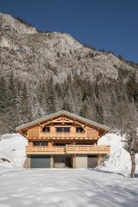 a log cabin in the snow in front of a mountain at Chalet La Rocca in La Chapelle-dʼAbondance