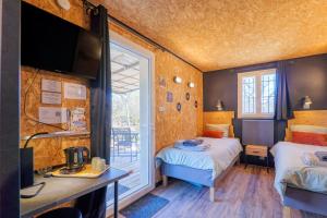 ein Zimmer mit zwei Betten, einem Schreibtisch und einem Fernseher in der Unterkunft Studio 315 in Villeneuve-de-Berg