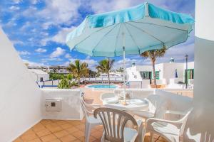 a patio with a table and a blue umbrella at Apartamentos Sal y Mar in Puerto del Carmen