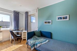 a room with a blue wall with a couch and a desk at Ferienwohnung Sterl 13 in Herscheid