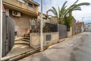 eine leere Straße mit einem Zaun und einer Palme in der Unterkunft Casa Flu in Assemini