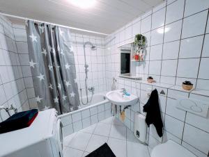 a white tiled bathroom with a sink and a shower at Wat Bickenbach in Bickenbach