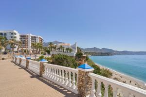 a white fence next to a beach with palm trees at Carabeo 19 in Nerja