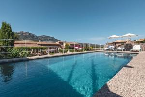 a swimming pool with blue water and umbrellas at Finca Can Nou in Sóller