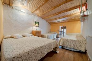 ein Schlafzimmer mit zwei Betten und einer Holzdecke in der Unterkunft Cal Cosials in La Morera de Montsant