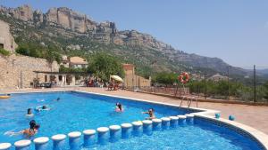 eine Gruppe von Menschen in einem Schwimmbad mit einem Berg in der Unterkunft Cal Cosials in La Morera de Montsant