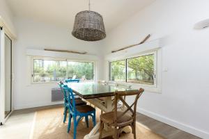 a dining room with a glass table and blue chairs at Pin Bleu in Moliets-et-Maa