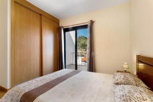 a bedroom with a bed and a large window at Casa da Pontinha in Machico