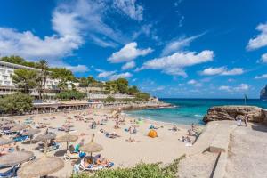 a group of people on a beach with umbrellas at Can Botana 12 in Cala de Sant Vicenc