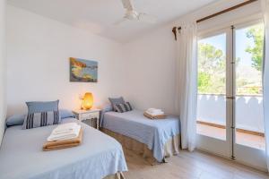 two beds in a room with a window at Can Botana 12 in Cala de Sant Vicenc +21 photos