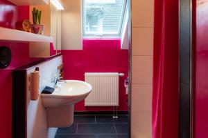 a bathroom with red walls and a sink and a window at s'Krumme Gustels Hüs in Bahlingen