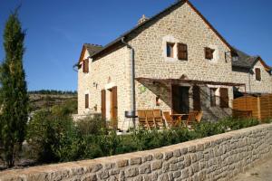 a stone house with chairs and a stone wall at Le Genévrier - Gites Rocheflamme in La Malène