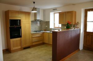 a kitchen with wooden cabinets and a black appliance at Le Genévrier - Gites Rocheflamme in La Malène