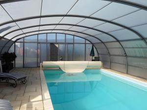 a swimming pool in a building with a glass ceiling at Le Genévrier - Gites Rocheflamme in La Malène