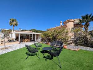 three chairs and a table on a lawn in front of a house at R-70 Oasis in Ciudad Quesada