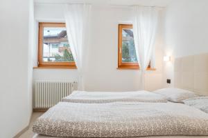 a white bedroom with two beds and two windows at Il Mondo di Patty 3 in Pera